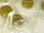 『たんぽぽ茶飴』の写真　緑色のたんぽぽ茶飴が透明の袋に個包装されています。
